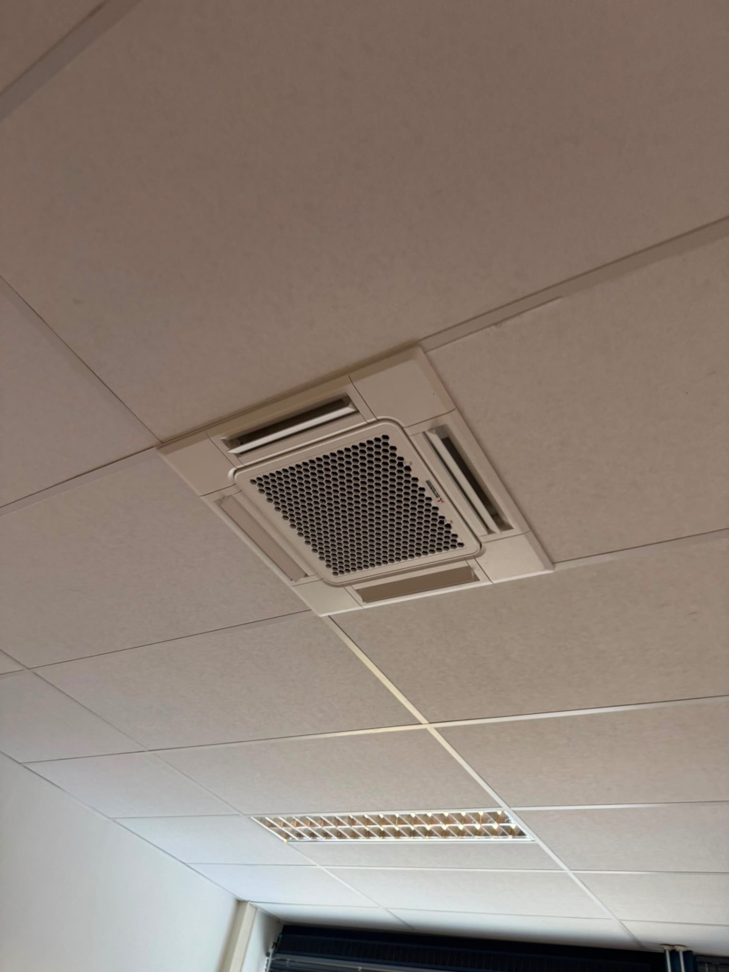 Cassette-unit in een kantoorruimte met systeemplafond en verlichting